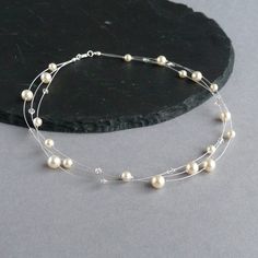 This cream floating pearl necklace would make the perfect gift for a bride or her bridesmaids. Each multi-strand necklace is created by scattering cream Swarovski pearls and Swarovski crystals along lengths of silver wire. This ivory pearl 3 strand necklace measures 18 inches / 46cm in length and is completed with a silver plated lobster clasp. Each dainty necklace is finished with a 2 inch extension chain to allow you to adjust the necklace length to fit. Your jewellery will arrive gift wrapped and ready to present as a gift or to enjoy as a treat to yourself. All of my items are packaged with care to ensure they arrive in perfect condition. --------------------- Matching items available --------------------- Cream floating bracelet: https://www.etsy.com/listing/632590907 Cream pearl stud Adjustable Cream Necklace For Wedding, Chunky Stone Necklace, Pearl Wedding Jewelry, Floating Pearl Necklace, Chunky Pearl Necklace, Necklaces Pearl, Three Strand Necklace, Fused Glass Necklace, Fan Necklace