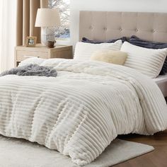 a bed with white comforter and pillows in a bedroom