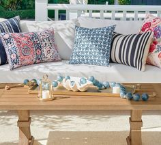 a white couch with pillows on top of it next to a wooden table and bench