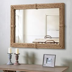 a mirror that is on the wall above a table with candles and a candle holder