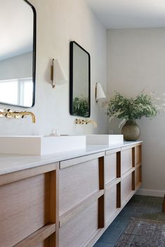 a bathroom with two sinks and mirrors on the wall