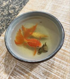 two goldfish in a bowl on a table