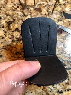 a hand holding a small black object on top of a counter