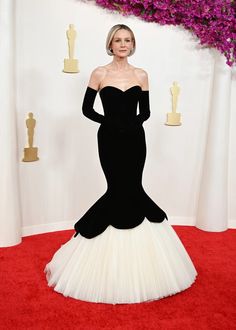 an older woman in a black and white gown on the red carpet with purple flowers