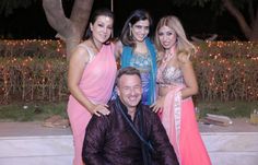 three women and one man posing for a photo together in front of a tree at night