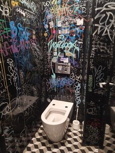 a bathroom with graffiti all over the walls and toilet bowl in the middle of the floor