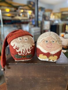 two knitted santa claus hats sitting on top of a wooden table next to each other