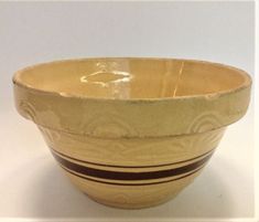 a yellow and brown bowl sitting on top of a white table