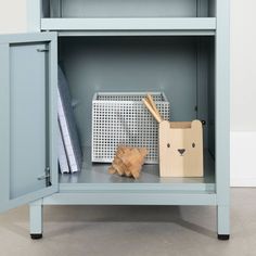 a blue cabinet with a cardboard box and other items on it's shelf next to a wooden animal figure