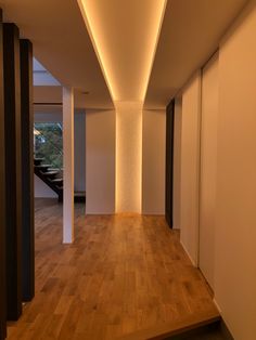 an empty room with wooden floors and white walls, lit by recessed lighting on the ceiling