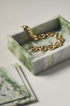 a marble box with a gold chain on it and two matching coasters in the background