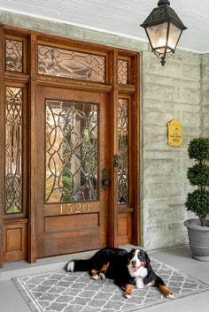 a dog is laying on the front door mat in front of an entrance with glass panels