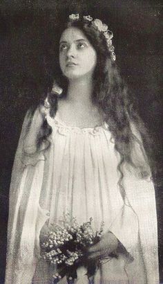 an old black and white photo of a woman with long hair wearing a wedding dress