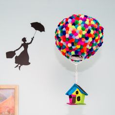 a balloon with a house on it and a girl holding an umbrella flying over the house