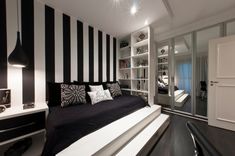 a black and white striped room with a futon in the corner, bookshelves on either side