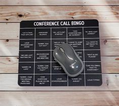 a computer mouse sitting on top of a black and white board with the words conference call bingo