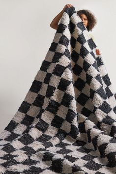 a woman holding up a black and white checkered blanket