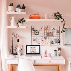 a white desk topped with a laptop computer next to a wall covered in pictures and plants