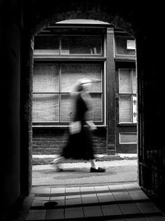 black and white photograph of woman walking through an archway