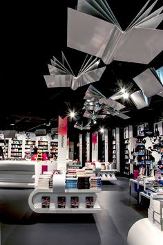 the interior of a book store with many books on shelves and lights hanging from the ceiling