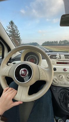 a person sitting in a car with their hand on the steering wheel while driving it