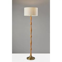 a wooden floor lamp with a white shade