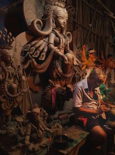 a man sitting in front of a wooden statue