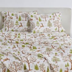 an image of a bed with deer and trees printed on the sheet set in white