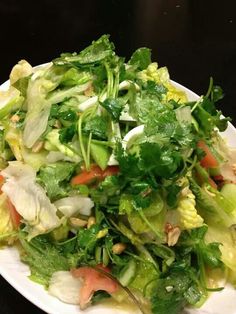 a salad with lettuce, carrots and other vegetables on a white plate