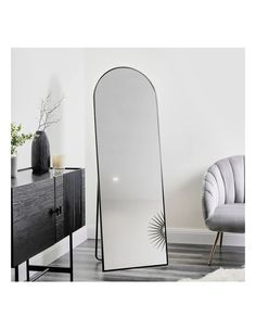 a large mirror sitting on top of a wooden floor next to a chair and table