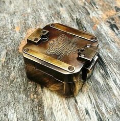 an old metal box sitting on top of a wooden table next to a bottle opener