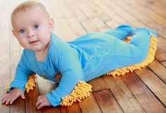 a baby is laying on the floor with a mop