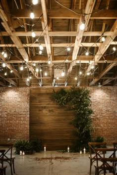 an indoor wedding venue with wooden walls and greenery on the wall, surrounded by candles