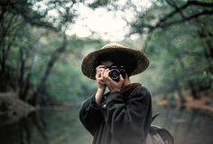 a person with a camera taking pictures in the woods