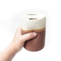 a hand is holding a cup with something in it