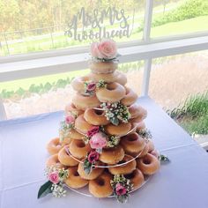 a cake made out of doughnuts and flowers on a table in front of a window