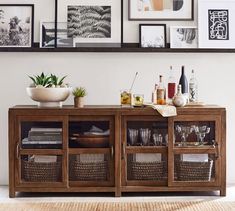 an entertainment center with pictures on the wall and wine glasses in baskets under it, next to a rug