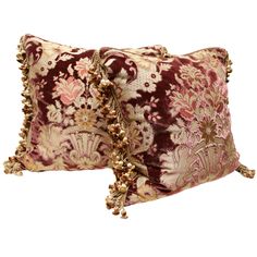 two decorative pillows with tassels on the ends, one in burgundy and gold