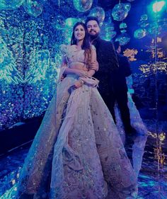 a man and woman standing next to each other in front of disco ball backdrops