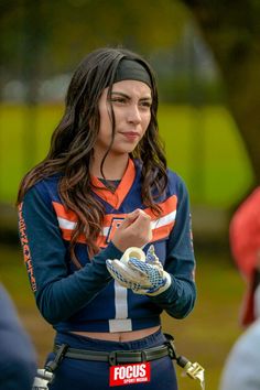 a woman in an orange and blue uniform is holding a soccer ball with her hands