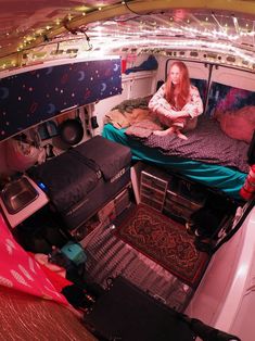 a woman sitting on top of a bed in the back of a van filled with furniture