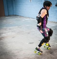 a man riding a skateboard down a cement floor next to a blue brick wall