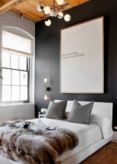 a bedroom with black walls, white bedding and fur rugs on the floor