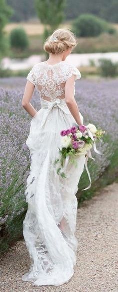 a woman in a white dress is walking through lavender fields