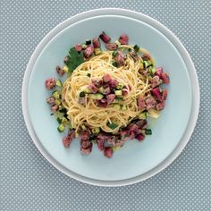 a white plate topped with pasta and veggies on top of a blue table