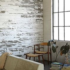 a living room filled with furniture next to a window and white painted wood paneling