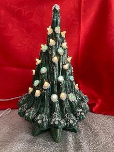 a glass christmas tree with white and green balls on it's top, sitting on a table