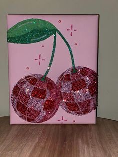 two cherries on a pink background with green leaves and sparkles in the center