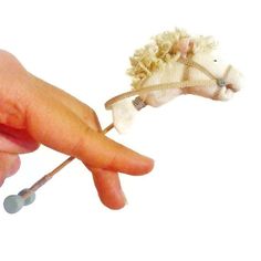 a hand holding a tiny toy sheep and needle tip nose plugs on it's thumb