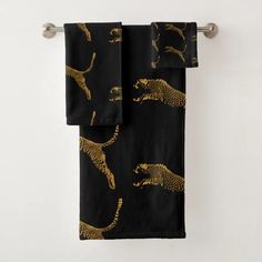 two black towels with gold cheetah and leopards on them hanging from a towel rack